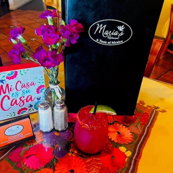 Maria's Restaurant menu, a vibrant drink, salt and pepper shakers, and flowers on a colorful table runner.