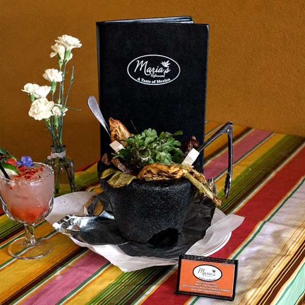Maria's Mexican restaurant table with a colorful tablecloth, a cocktail, and a large dish.